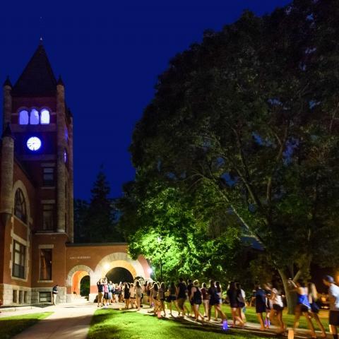 夜晚，学生们在汤普森大厅的拱门下散步