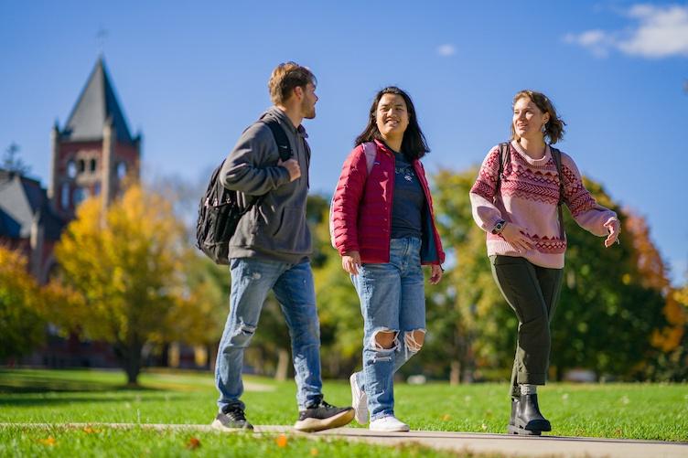 三个学生走在校园里，背景是汤普森大厅